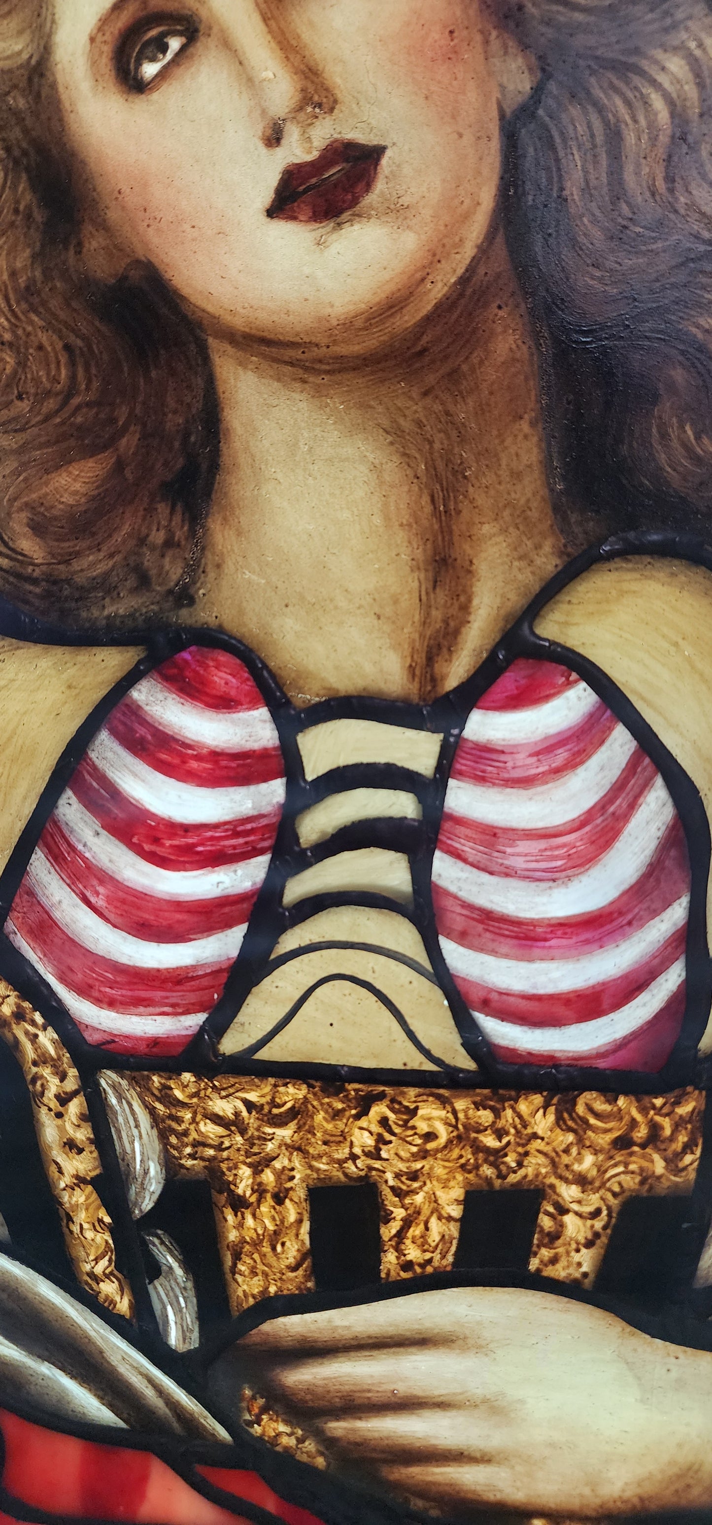 Close-up of a detailed painting with a face, striped elements, and gold accents.